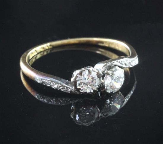 An early 20th century 18ct gold and platinum, two stone diamond crossover ring, size L.
